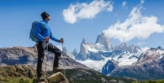 A hiker resting below snowy peaks